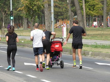 Rear view of people walking on road in city