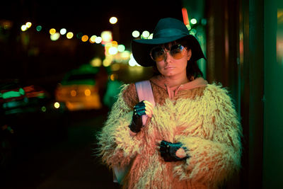 Woman wearing hat while standing outdoors at night