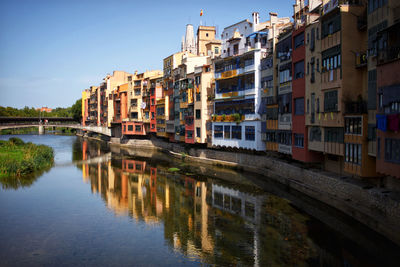 Bridge over river by buildings against sky