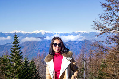 Portrait of young woman against snowcapped mountains during winter