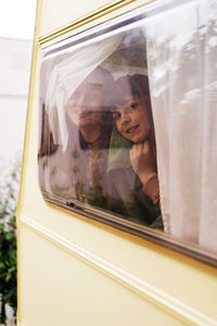 Children smiling while looking outside from the cabin of a motorhome