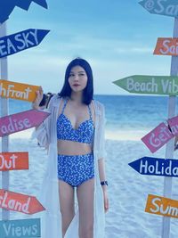 Young woman standing by sea against sky