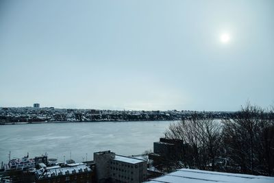 City by river against clear sky during winter