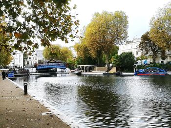 Boats in river by trees against sky