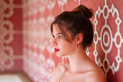 Side view of woman standing by wall