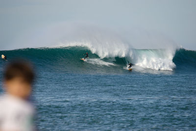 People surfing in sea against sky