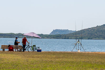 People sitting on beach against clear sky