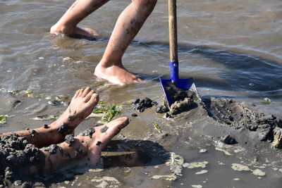 Low section of man surfing on sea shore