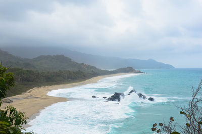 View of calm beach against cloudy sky