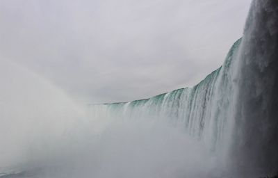 Scenic view of waterfall against mountains during winter