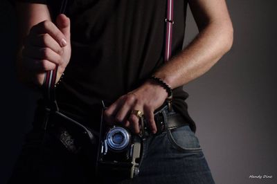 Midsection of man holding hands while standing against black background