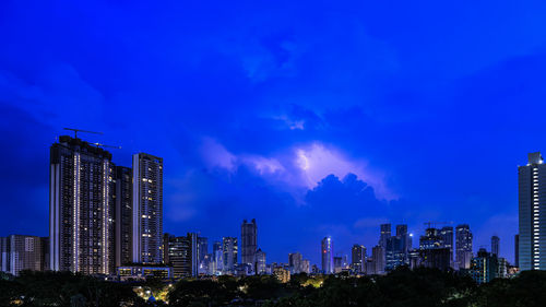 Panoramic view of illuminated buildings against sky at night further enhanced by  stunning lightning 