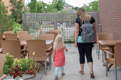 Rear view of mother with daughter walking at outdoor cafe