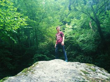Full length of man standing on rock in forest