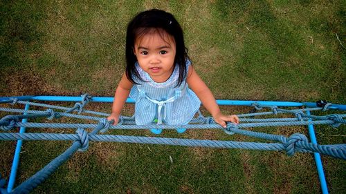 Portrait of cute girl climbing on rope in playground