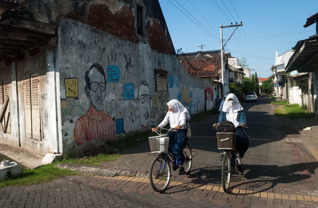 building exterior, architecture, built structure, bicycle, transportation, graffiti, street, mode of transport, land vehicle, stationary, wall - building feature, day, city, residential structure, sunlight, outdoors, parking, residential building