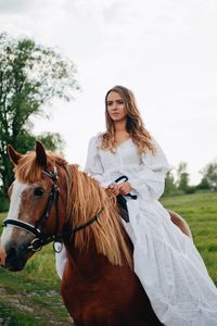 Young woman riding horse on field