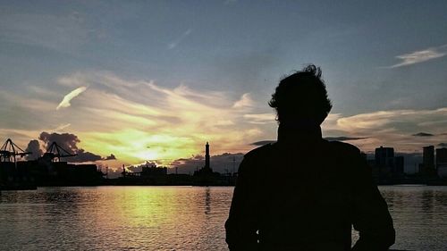 Silhouette of people in water at sunset