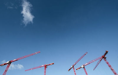 Low angle view of cranes against clear blue sky