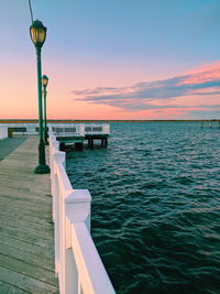 Pier over sea against sky during sunset