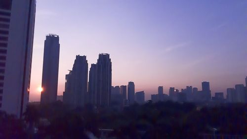 Modern buildings in city against sky during sunset