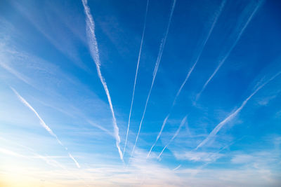 Low angle view of vapor trails against blue sky