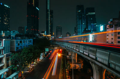 Light trails on street amidst buildings in city at night