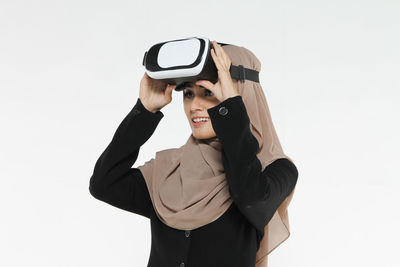 Smiling woman wearing virtual reality against white background