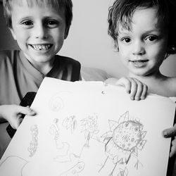 Portrait of siblings holding drawing at home