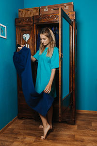 Full length of woman standing against blue wall