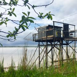 House on field by lake against sky