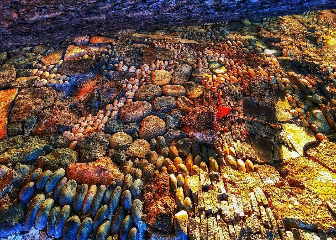 HIGH ANGLE VIEW OF MULTI COLORED ROCKS ON SEA