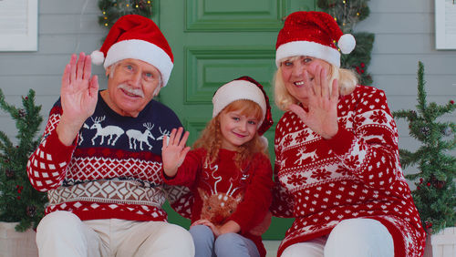 Portrait of smiling senior couple with daughter sitting on steps outdoors