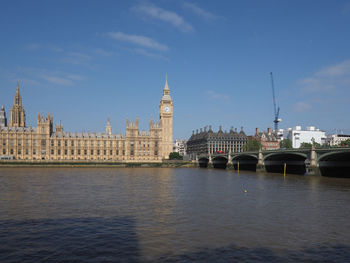 Buildings by river against sky