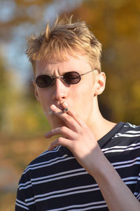 Portrait of young man with sunglasses against blurred background