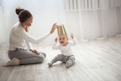Cheerful baby boy having fun with mother on floor, mum gently embraces the blond son 
