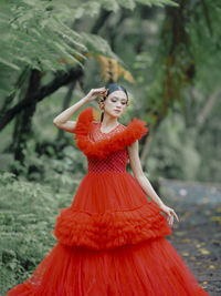 Portrait of young woman standing against trees