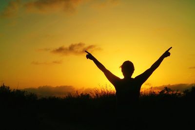 Silhouette woman standing against orange sky during sunset