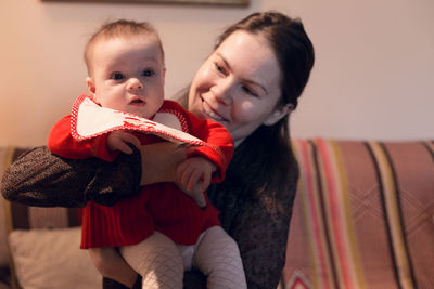 Smiling mother carrying daughter at home