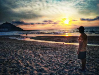 Man standing on beach against sky during sunset