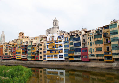 Buildings by river against sky in city