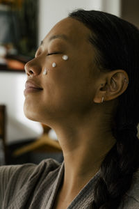 Young woman with eyes closed and cream on face