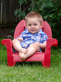 Young boy in red chair poses happily