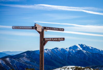 Information sign on snowcapped mountains against sky