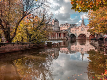 Arch bridge over river against sky during autumn