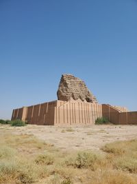 Castle on field against clear blue sky