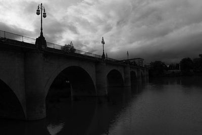 Bridge over river against cloudy sky