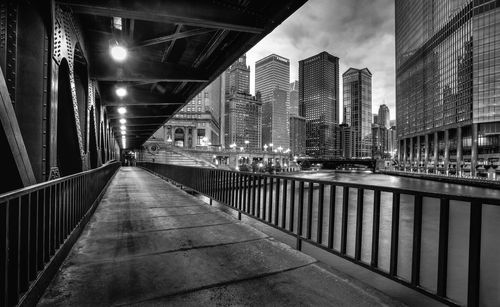 Illuminated footbridge amidst buildings in city