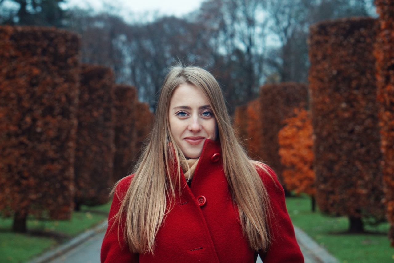 hair, long hair, portrait, hairstyle, one person, blond hair, looking at camera, tree, focus on foreground, young women, women, young adult, beauty, smiling, beautiful woman, front view, headshot, lifestyles, real people, teenager, straight hair, warm clothing