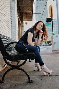 Portrait of teenage girl sitting on bench in city